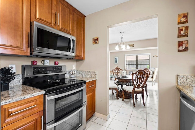 kitchen with stainless steel appliances, light stone countertops, and a notable chandelier