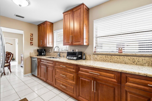 kitchen with light stone counters, light tile patterned flooring, dishwasher, and sink