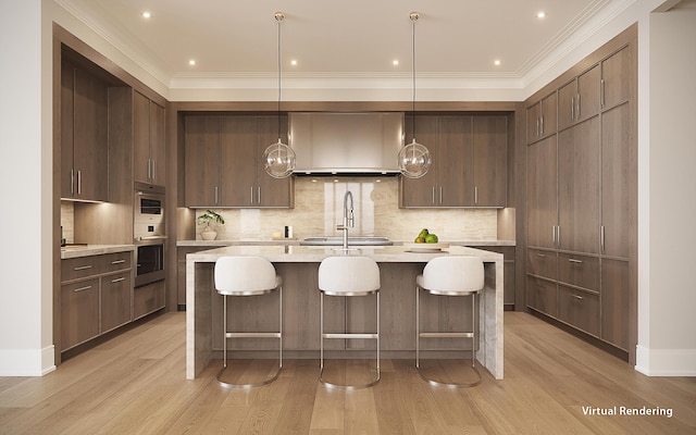 kitchen with pendant lighting, ornamental molding, wall chimney exhaust hood, and light hardwood / wood-style floors