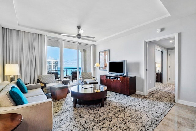 living room with ceiling fan and a raised ceiling