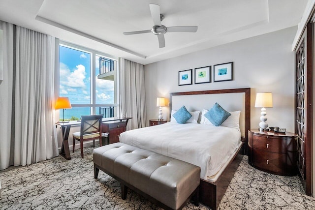 carpeted bedroom with a tray ceiling, ceiling fan, and a water view