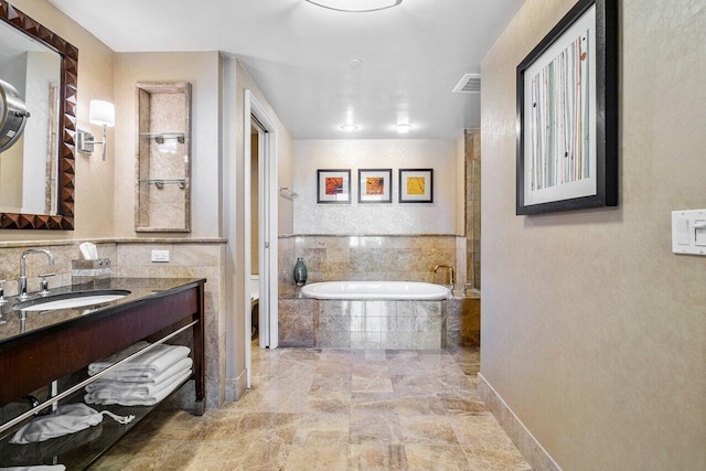 bathroom featuring tiled tub, vanity, decorative backsplash, and toilet