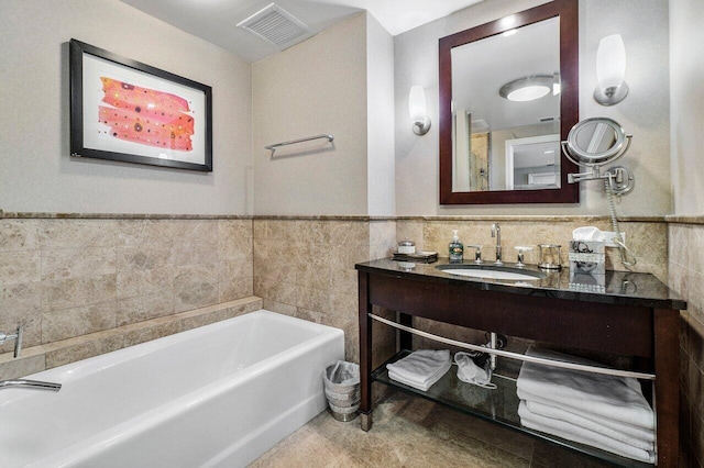 bathroom with vanity, a tub, and tile walls