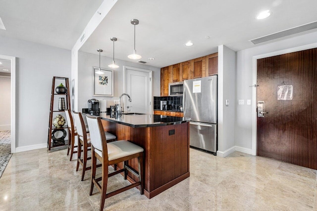 kitchen with sink, a breakfast bar area, hanging light fixtures, appliances with stainless steel finishes, and kitchen peninsula