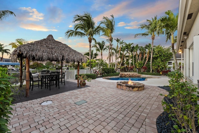 patio terrace at dusk featuring a fire pit and a gazebo