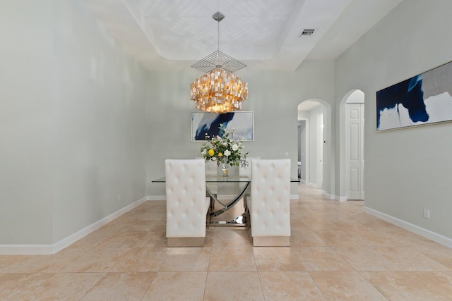 unfurnished dining area with light tile patterned flooring, a notable chandelier, and a tray ceiling