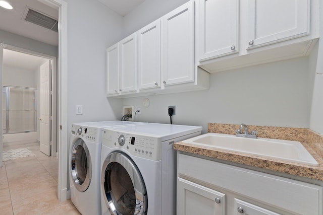 washroom with cabinets, independent washer and dryer, sink, and light tile patterned floors