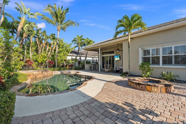 view of pool with an in ground hot tub, ceiling fan, exterior kitchen, and a patio