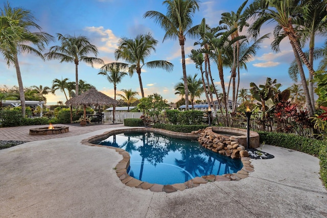 pool at dusk with a gazebo, an outdoor fire pit, an in ground hot tub, and a patio