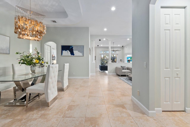 dining space featuring light tile patterned floors, a notable chandelier, and ornate columns