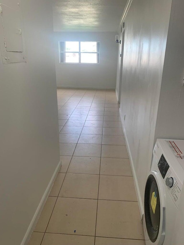 corridor featuring washer / dryer, electric panel, a textured ceiling, and light tile patterned flooring