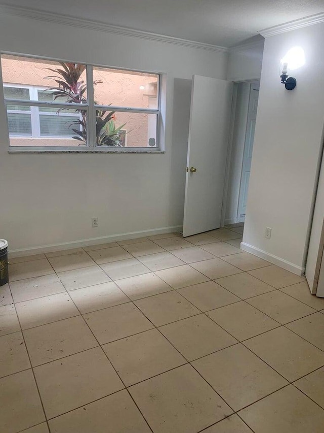 empty room featuring ornamental molding and light tile patterned flooring