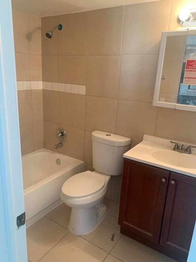 full bathroom featuring tile walls, tiled shower / bath combo, vanity, toilet, and tile patterned floors