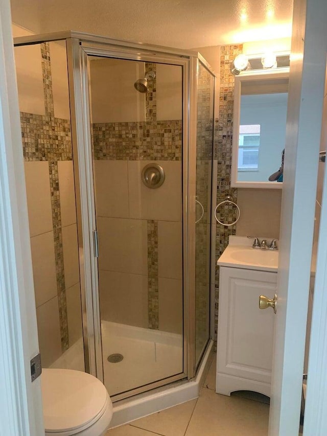 bathroom with toilet, sink, tile patterned floors, and a shower with shower door