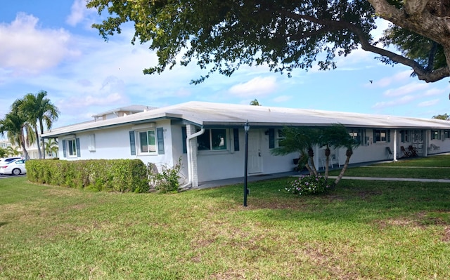 single story home with stucco siding, a carport, and a front yard