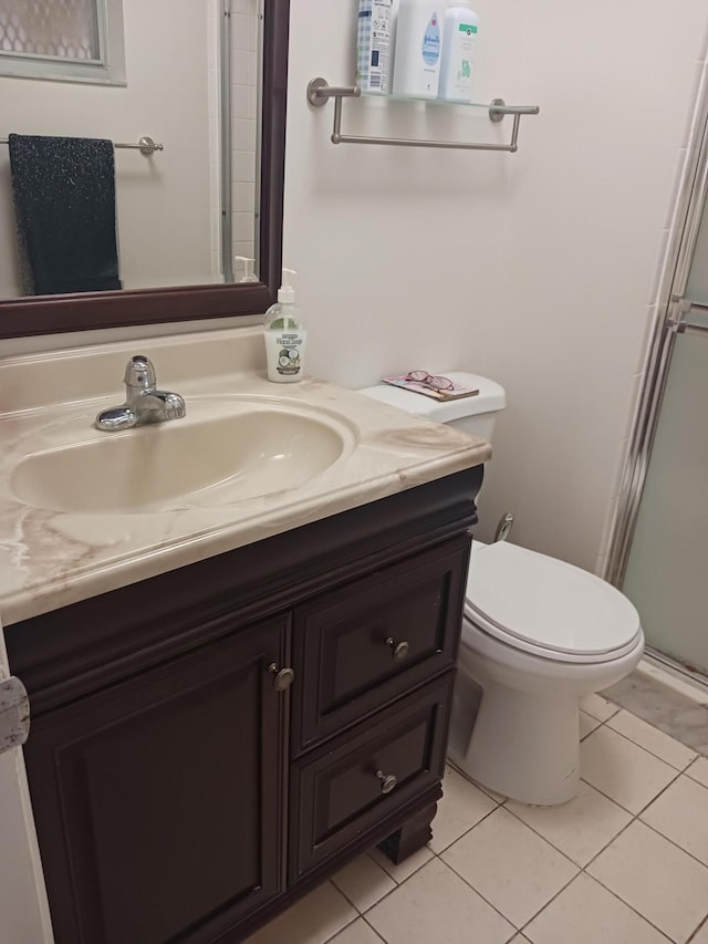 full bath with a shower with door, vanity, toilet, and tile patterned floors