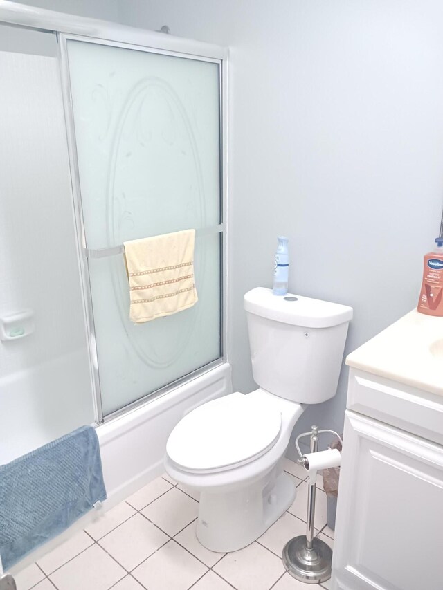 bathroom featuring tile patterned flooring, vanity, a shower with door, and toilet