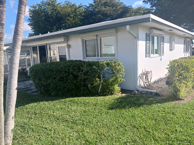 view of side of property with a lawn and stucco siding