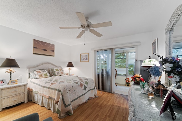 bedroom featuring access to exterior, wood-type flooring, a textured ceiling, and ceiling fan