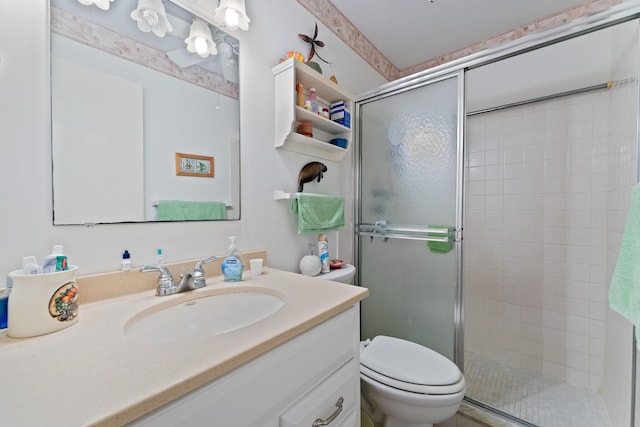 bathroom with a shower with door, vanity, and toilet