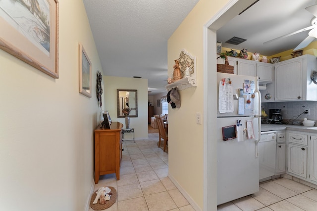 kitchen with white cabinetry, backsplash, white appliances, and light tile patterned flooring