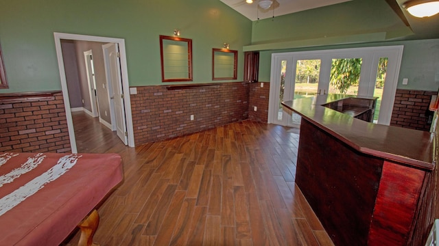 interior space with hardwood / wood-style flooring, lofted ceiling, brick wall, and french doors