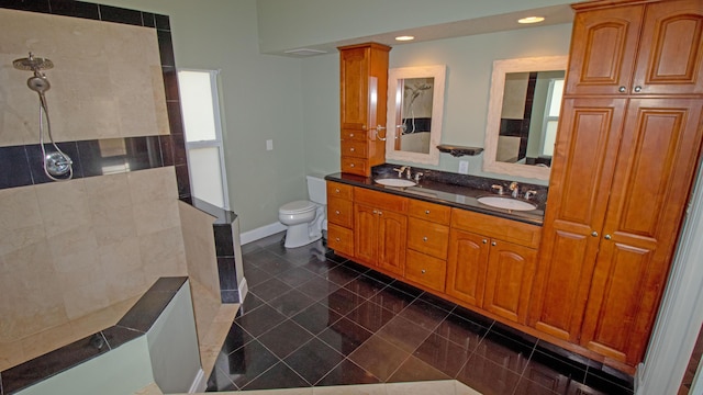 bathroom featuring toilet, decorative columns, a tile shower, vanity, and tile patterned flooring