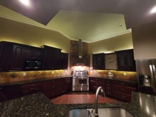 kitchen featuring sink, stainless steel appliances, wall chimney range hood, and lofted ceiling