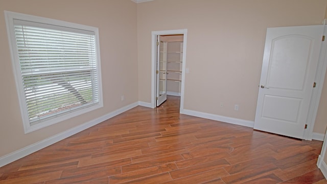 unfurnished bedroom featuring hardwood / wood-style flooring, a walk in closet, and a closet