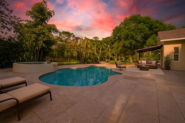 14717 11th Ter, Loxahatchee Groves, FL 33470 - pool at dusk featuring an outdoor hangout area, a patio area, and a pool with connected hot tub