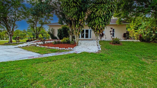 14717 11th Ter, Loxahatchee Groves, FL 33470 - view of property hidden behind natural elements with stucco siding, a front yard, and french doors