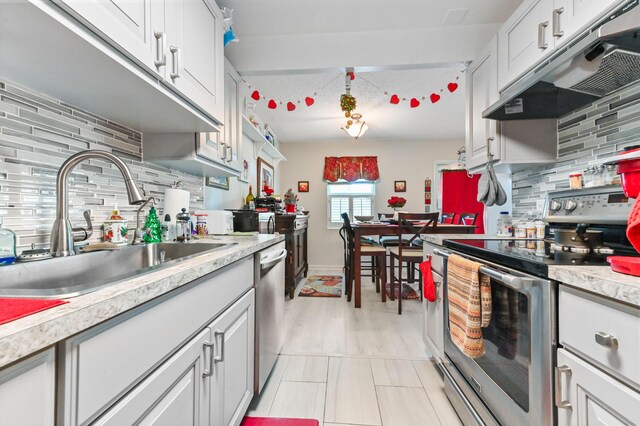 kitchen with tasteful backsplash, sink, white cabinets, and appliances with stainless steel finishes