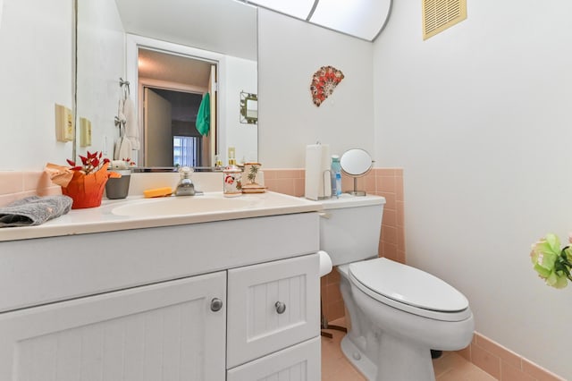 bathroom with vanity, tile patterned flooring, tile walls, and toilet