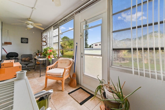 sunroom featuring ceiling fan and a water view