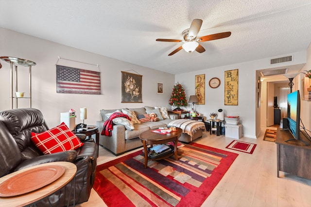 living room with ceiling fan, hardwood / wood-style floors, and a textured ceiling