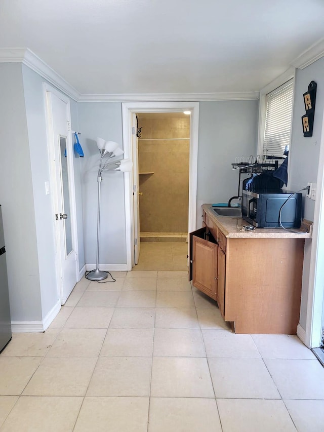 kitchen with crown molding, light tile patterned floors, and stainless steel refrigerator