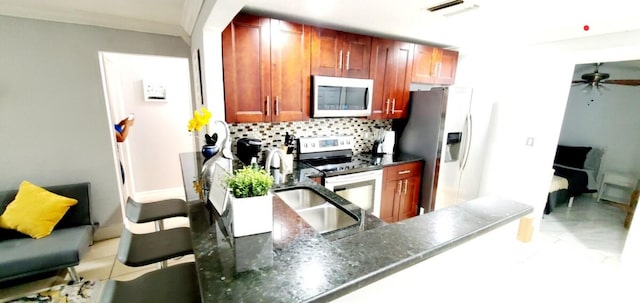 kitchen with dark stone countertops, decorative backsplash, kitchen peninsula, stainless steel appliances, and crown molding