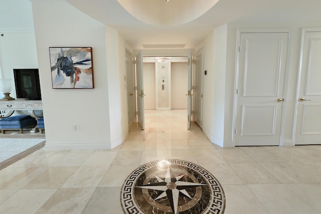 corridor with light tile patterned floors and a tray ceiling