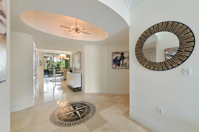 hall with an inviting chandelier and a tray ceiling