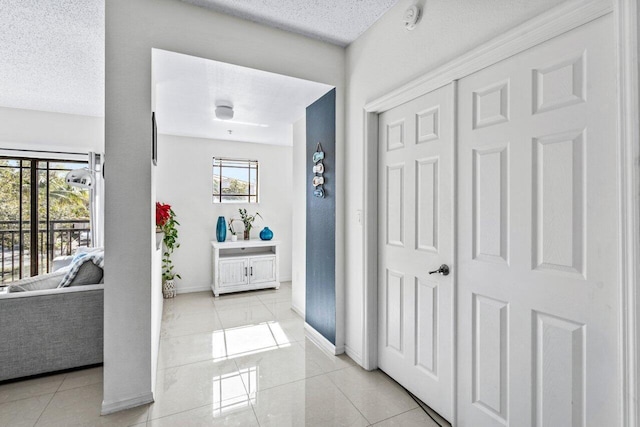 corridor featuring light tile patterned floors and a textured ceiling