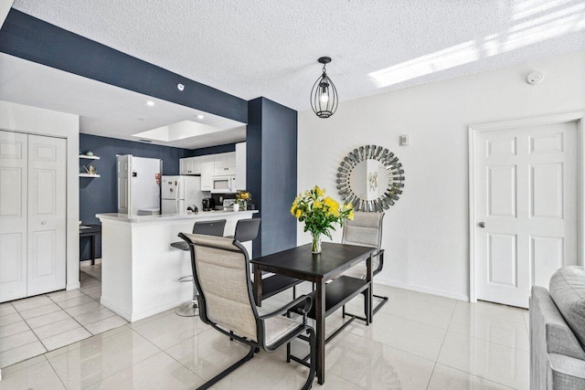 dining space featuring light tile patterned flooring and a textured ceiling