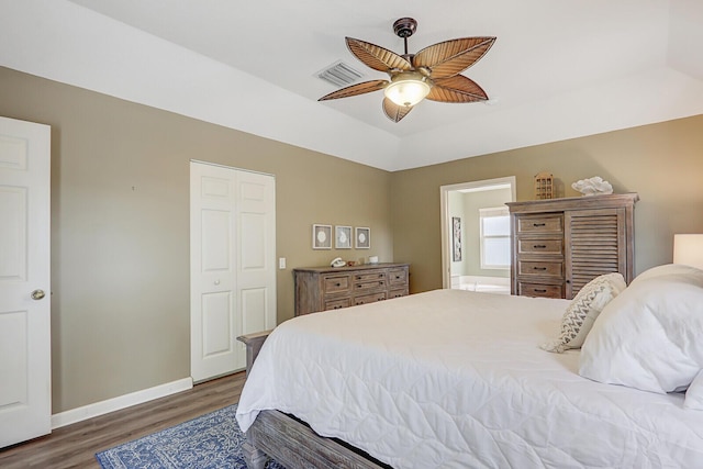 bedroom featuring lofted ceiling, dark hardwood / wood-style flooring, ceiling fan, ensuite bath, and a closet