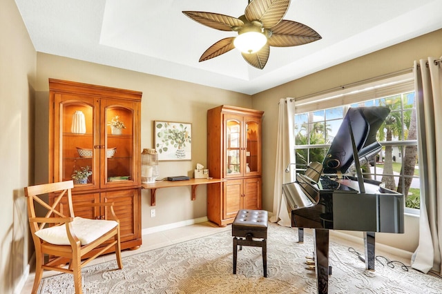 sitting room with a raised ceiling, ceiling fan, and light tile patterned flooring