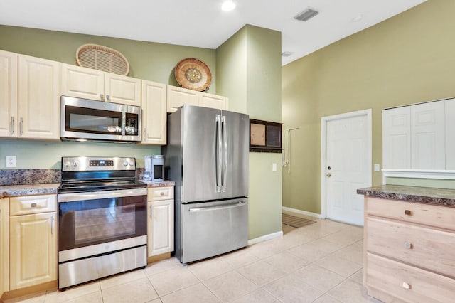 kitchen featuring a towering ceiling, stainless steel appliances, and light tile patterned flooring