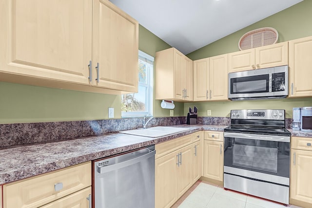 kitchen featuring sink, vaulted ceiling, stainless steel appliances, and light tile patterned flooring