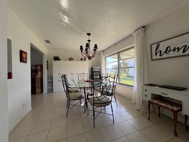 dining area with light tile patterned flooring, a chandelier, and a textured ceiling