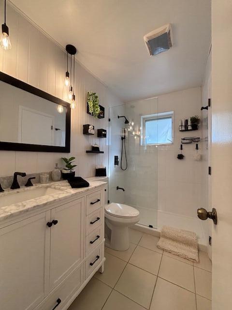 bathroom featuring tiled shower, vanity, toilet, and tile patterned flooring