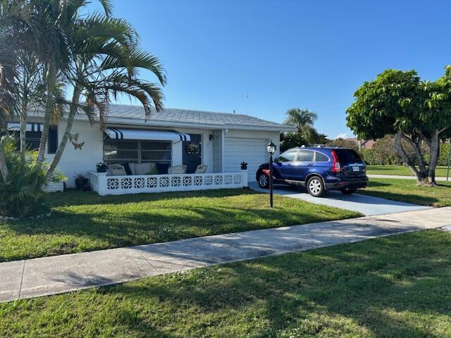 view of front of house with concrete driveway, an attached garage, and a front lawn