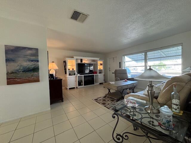 living room with light tile patterned flooring, visible vents, and a textured ceiling