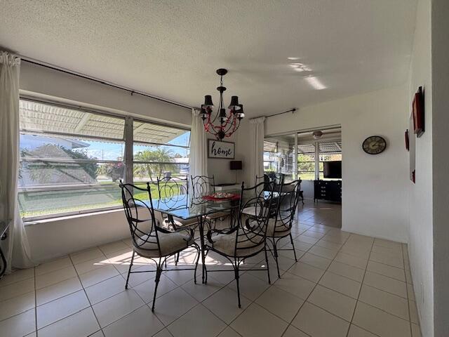 dining room with light tile patterned flooring, a chandelier, and a textured ceiling